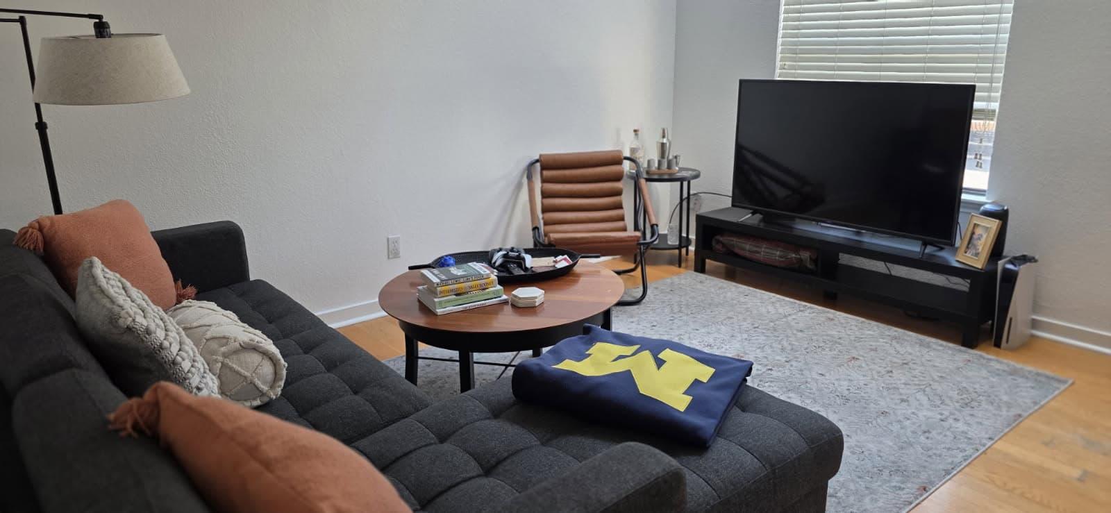 Rental living room with a charcoal sectional and a round coffee table